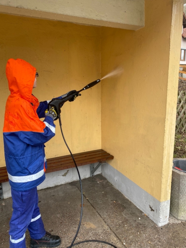 Reinigung der Bushaltestelle in Helba. Ein Jugendfeuerwehrmitglied mit Hochdruckwasserspritze